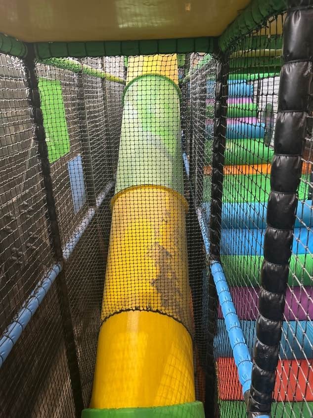 Stained yellow tube slide seen through the frame netting before a clean