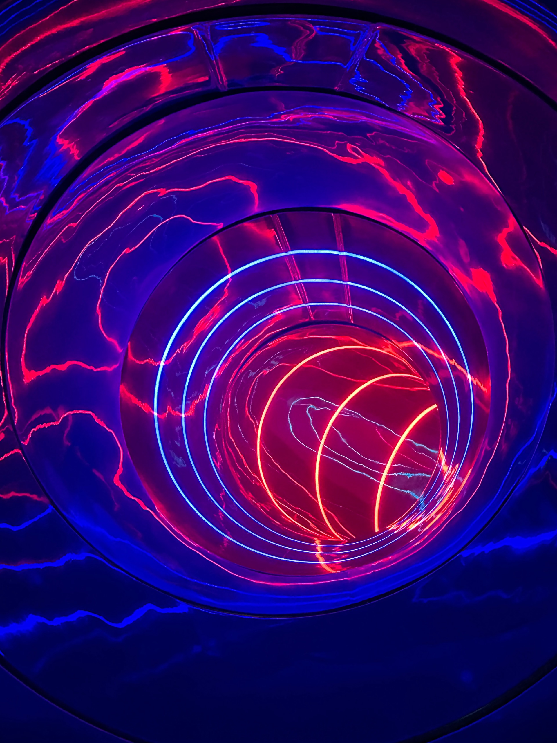 Looking into the LED spiral tube with concentric pink, blue and orange light rings