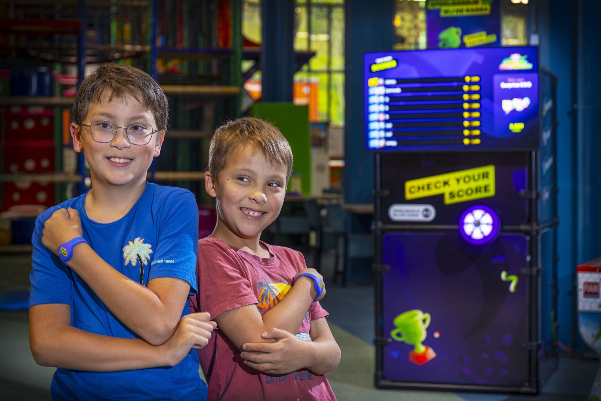 Children wearing Ninja Tag wristbands in front of the Check Your Score kiosk